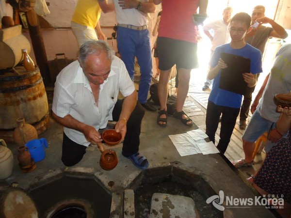 조지아 전통 항아리 크베물리에서 조지아 사람들이 황토 와인 그릇에 와인을 담고 있다 , 손에 들고 있는 조지아 전통 황토 와인 잔 @뉴스코리아 박철호 특파원