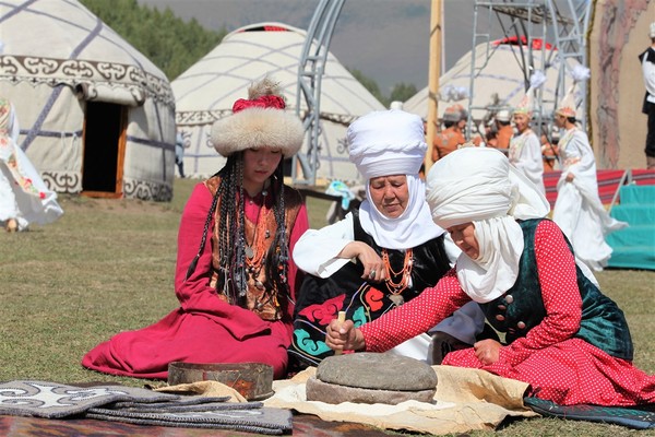 ▲사진 : 키르기스스탄 전통복장을 입은 여인들이 맷돌을 돌려서 곡식을 가루로 만드는 모습 