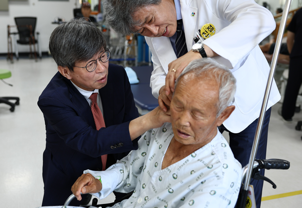 이기철 청장이 6.25전쟁 참전용사 정인화(93세) 어르신의 귀 뒤 총상을 살펴보며 위로하고 있다. @재외동포청