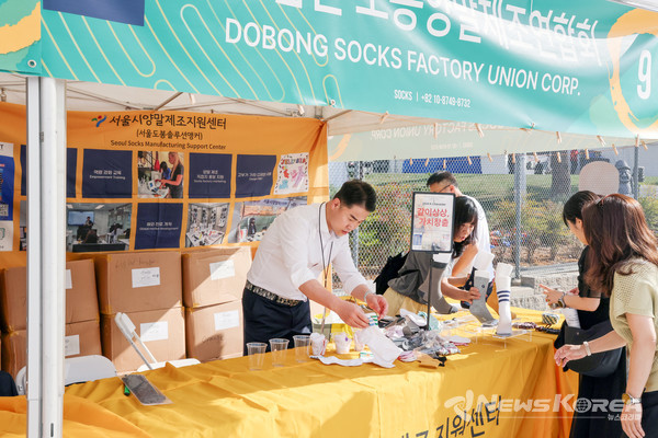 ▲오언석 도봉구청장이 지난해 9월 미국 로스앤젤레스에서 개최된 LA한인축제에서 손님을 맞이하기 전 도봉구 양말 제품을 정리하고 있다(2024. 9. 26. 미국 로스앤젤레스 @도봉구