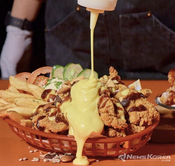▲고소한 치즈 소스가 바삭한 치킨 위로 흘러내리는 장면 – 굿 치킨의 시그니처 메뉴 ‘범벅’의 풍미를 시각으로 먼저 맛보게 한다. @뉴스코리아 신현권 특파원