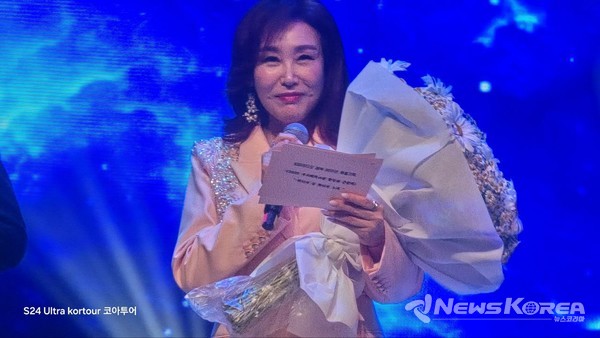 ▲‘2025 타슈켄트 한민족 큰잔치’ 무대에서 가수 주현미가 사회자이자 출연자로 따뜻한 메시지를 전하고 있다.꽃다발을 품에 안고 정성스레 준비한 멘트를 낭독하던 그녀는, 고려인 동포들과 관객들에게 깊은 공감과 감동을 선사했다. @뉴스코리아 신현권 동포기자