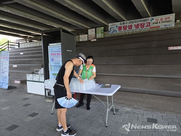 도봉구 주민이 중랑천 상계교 하부에 마련된 봉달샘 냉장고에서 생수를 가져가고 있다 @도봉구