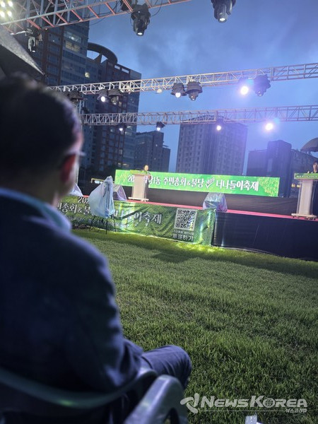 김행금 천안시의회 의장이 무대에서 인사말을 하고 있는 모습을 비를 맞으며 바라보고 있는 장혁 의원 @뉴스코리아 최신 기자